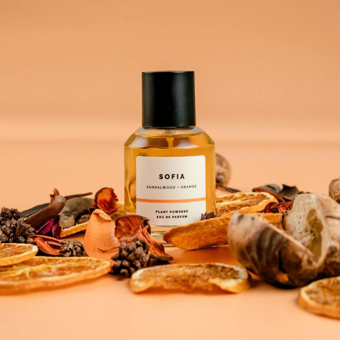Perfume bottle labeled 'Sofia' by ECO. Modern Essentials surrounded by dried fruits & herbs on a peach background.
